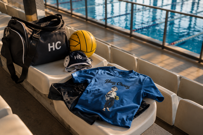 Sports bag on seat with water polo ball and cap, blue Huey Chewy water polo player t-shirt laid on top of clothes